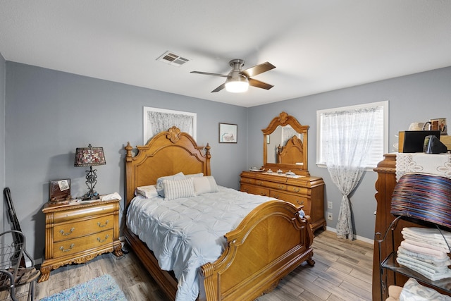 bedroom with ceiling fan, light wood-type flooring, visible vents, and baseboards