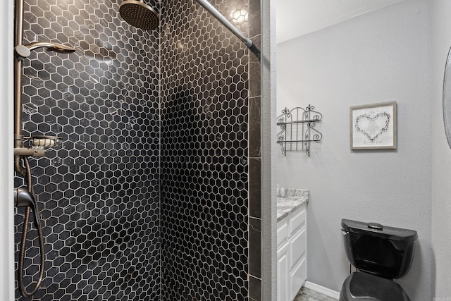 full bathroom with vanity, a tile shower, and toilet