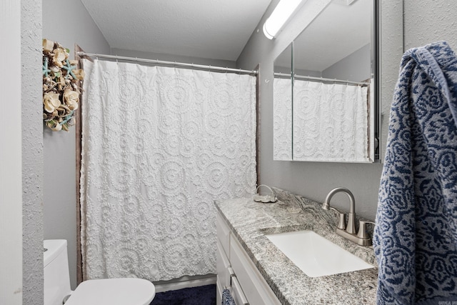 full bathroom with toilet, a textured ceiling, and vanity