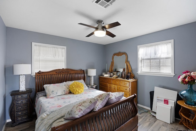 bedroom featuring visible vents, ceiling fan, baseboards, and wood finished floors