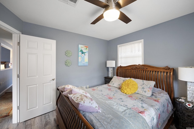 bedroom featuring ceiling fan, wood finished floors, and visible vents