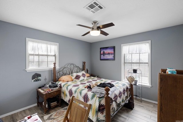 bedroom with multiple windows, light wood-type flooring, and visible vents