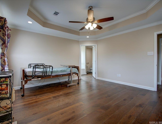 bedroom featuring visible vents, a tray ceiling, dark wood-style flooring, and ornamental molding