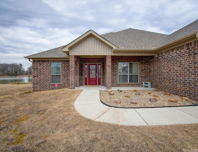 entrance to property with brick siding and roof with shingles