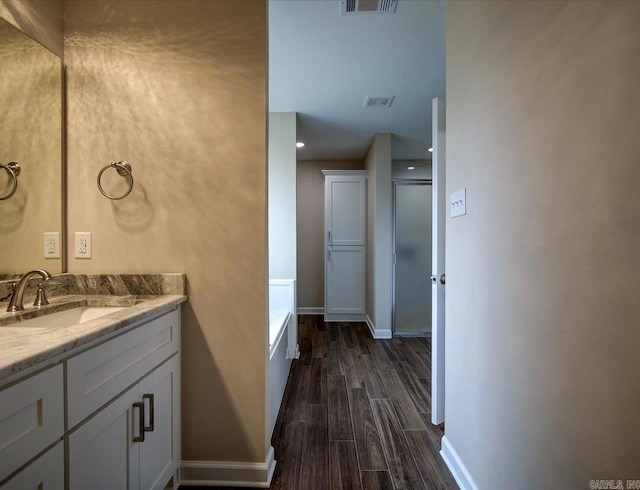 full bath featuring an enclosed shower, vanity, baseboards, and wood finished floors