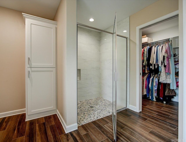 full bath with a stall shower, baseboards, a walk in closet, wood finish floors, and recessed lighting