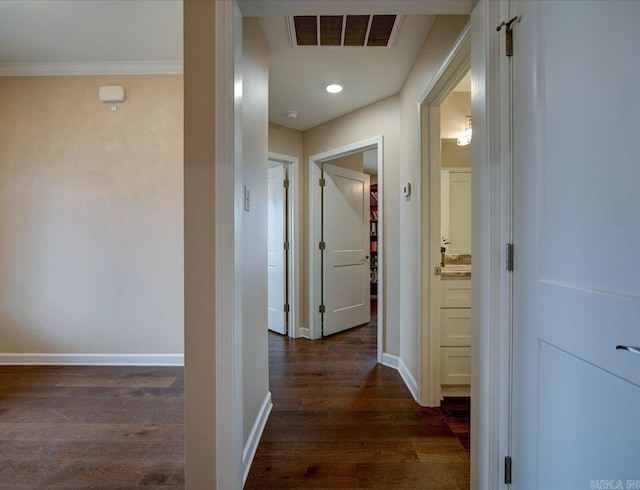 corridor with ornamental molding, dark wood-style flooring, visible vents, and baseboards