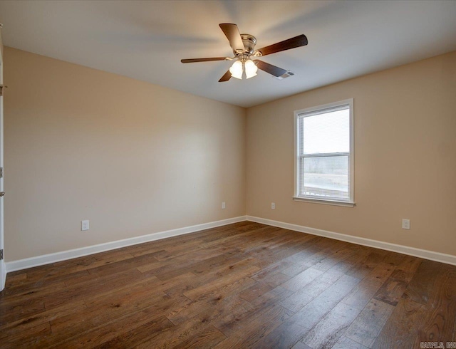 spare room with baseboards, dark wood finished floors, and a ceiling fan