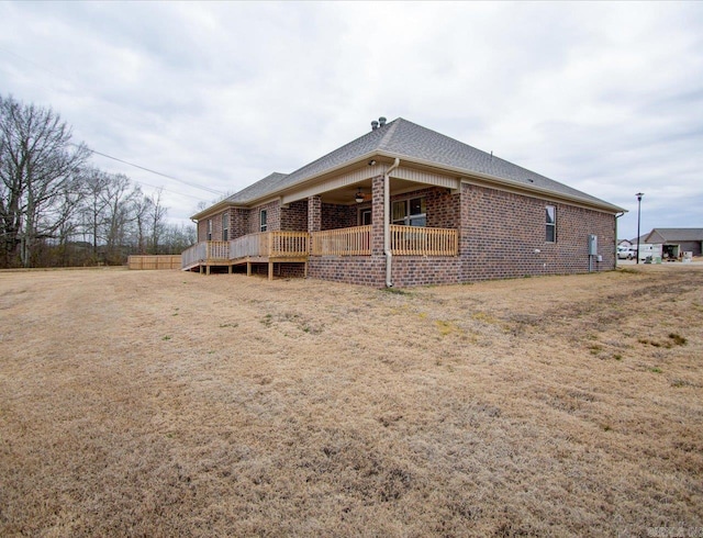 back of property featuring a shingled roof, brick siding, and ceiling fan