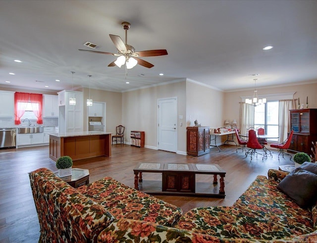 living room featuring ceiling fan with notable chandelier, recessed lighting, wood finished floors, and crown molding