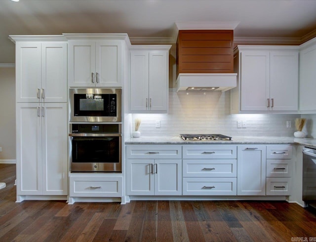 kitchen with light stone counters, custom range hood, appliances with stainless steel finishes, dark wood-type flooring, and white cabinetry