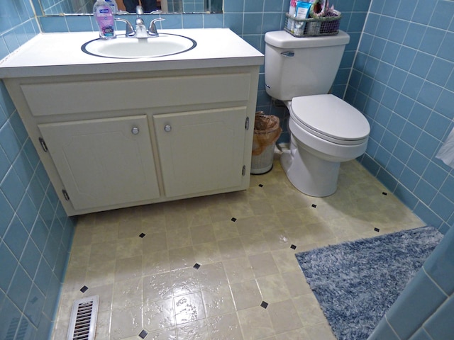 bathroom with tile walls, visible vents, vanity, and toilet