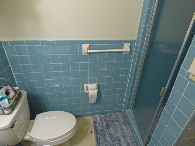 bathroom featuring a stall shower, wainscoting, toilet, tile patterned flooring, and tile walls