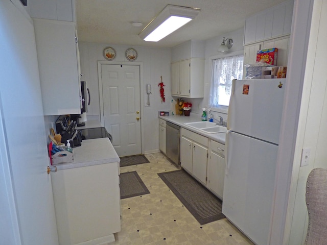 kitchen featuring freestanding refrigerator, light countertops, stainless steel dishwasher, light floors, and a sink