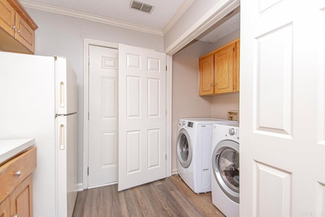 clothes washing area with visible vents, wood finished floors, crown molding, a textured ceiling, and separate washer and dryer