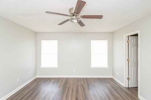 empty room with a wealth of natural light, a textured ceiling, baseboards, and wood finished floors