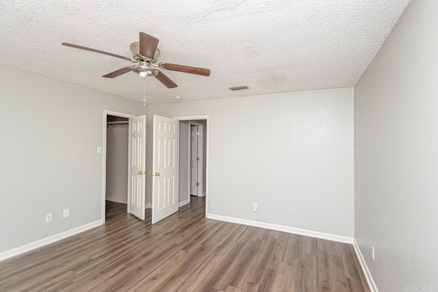 unfurnished bedroom featuring baseboards, a textured ceiling, visible vents, and wood finished floors