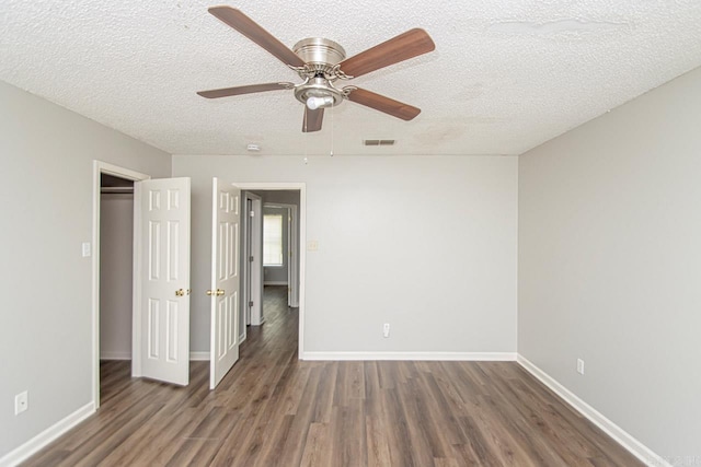 unfurnished bedroom featuring a textured ceiling, wood finished floors, visible vents, and baseboards