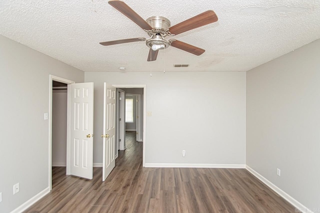 unfurnished bedroom featuring a textured ceiling, wood finished floors, a ceiling fan, visible vents, and baseboards