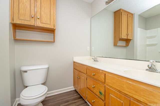 full bathroom with double vanity, a sink, toilet, and baseboards