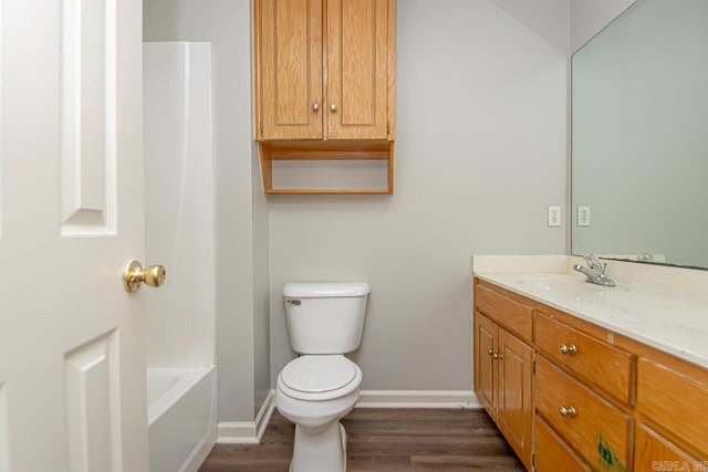 full bathroom with toilet, a bathing tub, vanity, wood finished floors, and baseboards