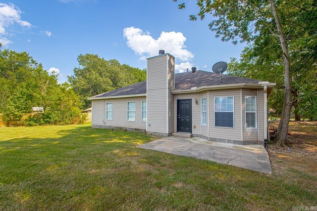 back of house featuring a patio area, a chimney, and a yard