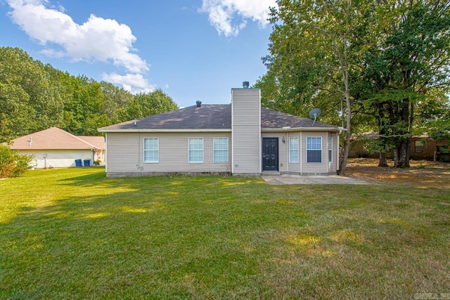 back of house with a patio, a lawn, and a chimney