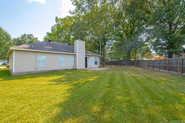 back of house featuring a fenced backyard, a chimney, and a yard