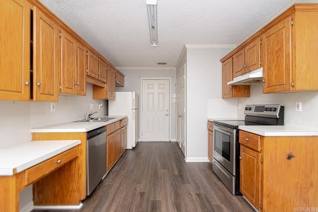 kitchen featuring under cabinet range hood, a sink, ornamental molding, appliances with stainless steel finishes, and dark wood finished floors