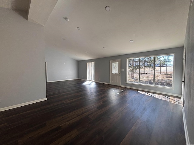 unfurnished living room featuring lofted ceiling, baseboards, and dark wood finished floors