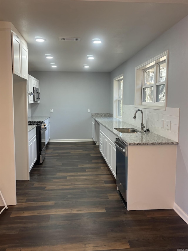 kitchen featuring light stone countertops, white cabinetry, appliances with stainless steel finishes, and a sink