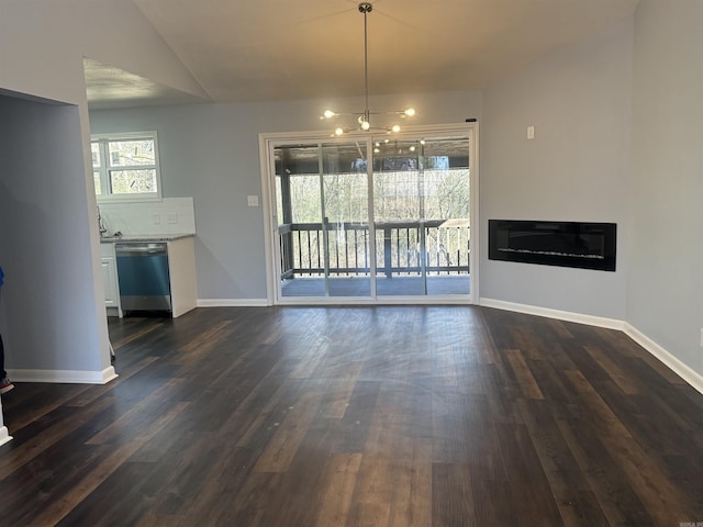 unfurnished dining area with a glass covered fireplace, a healthy amount of sunlight, dark wood finished floors, and baseboards