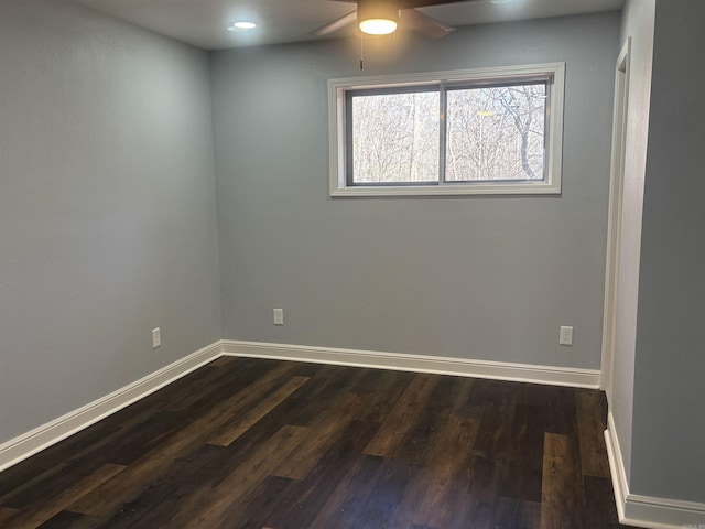 empty room featuring ceiling fan, dark wood-type flooring, and baseboards