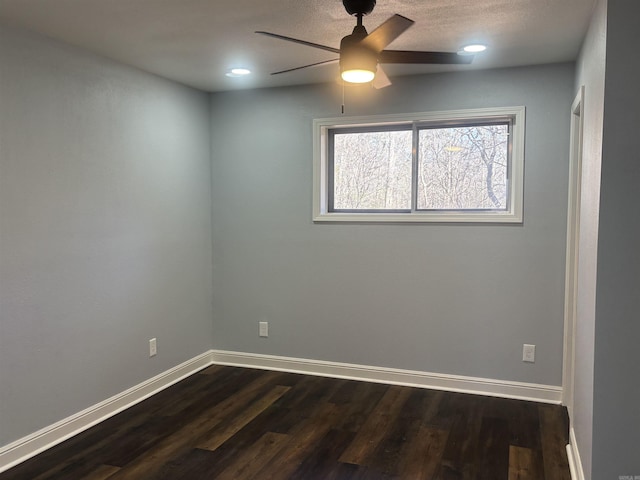 spare room featuring a ceiling fan, dark wood finished floors, and baseboards