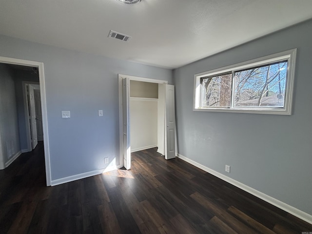 unfurnished bedroom featuring dark wood-style floors, baseboards, and visible vents