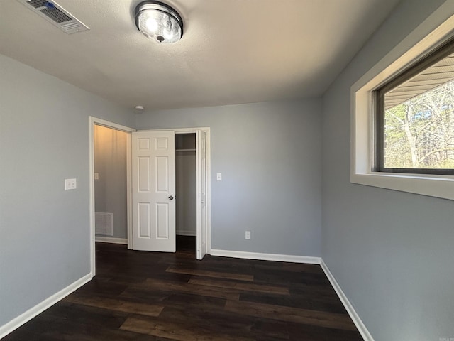 unfurnished bedroom with dark wood-style floors, baseboards, visible vents, and a textured ceiling