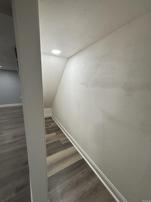 staircase featuring baseboards, vaulted ceiling, and wood finished floors