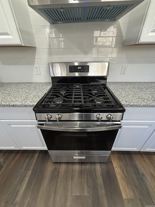 kitchen featuring stainless steel gas range oven, extractor fan, light stone counters, dark wood-style flooring, and white cabinets