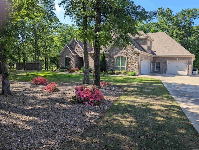 view of front of home with driveway, a garage, a shingled roof, stone siding, and a front lawn