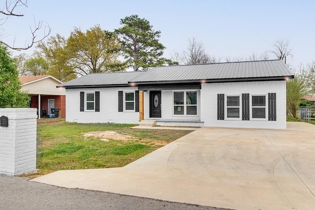 view of front of property featuring metal roof, brick siding, and a front yard