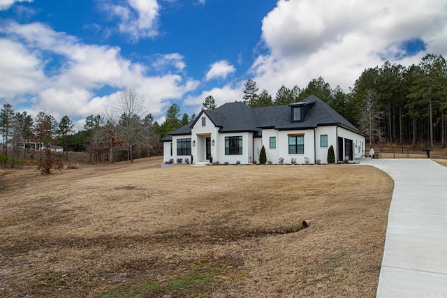 modern inspired farmhouse featuring a garage, driveway, a front lawn, and a shingled roof