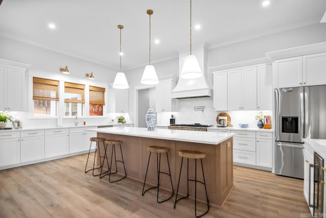 kitchen with white cabinetry, custom range hood, appliances with stainless steel finishes, and crown molding