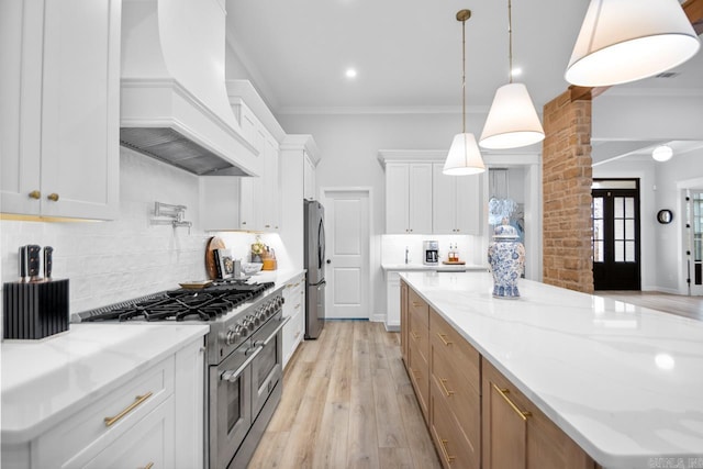 kitchen featuring light wood finished floors, custom exhaust hood, stainless steel appliances, crown molding, and white cabinetry