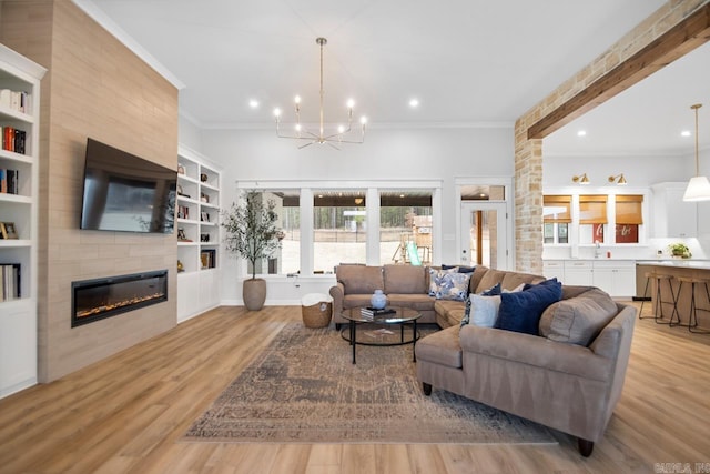 living room with a notable chandelier, crown molding, light wood finished floors, recessed lighting, and a large fireplace