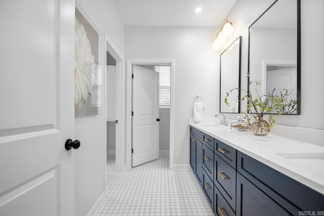 full bath featuring double vanity, recessed lighting, a sink, and baseboards