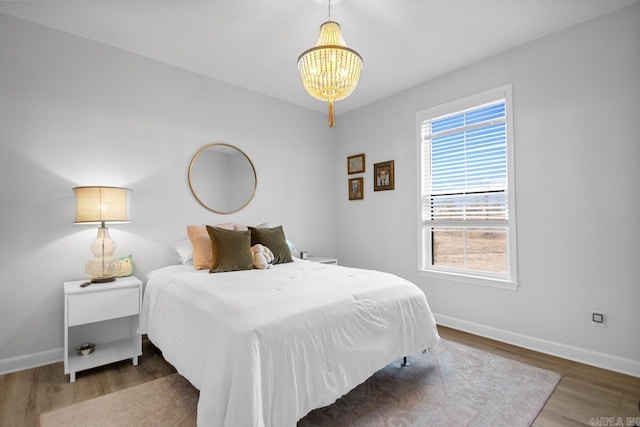 bedroom with a notable chandelier, baseboards, and wood finished floors