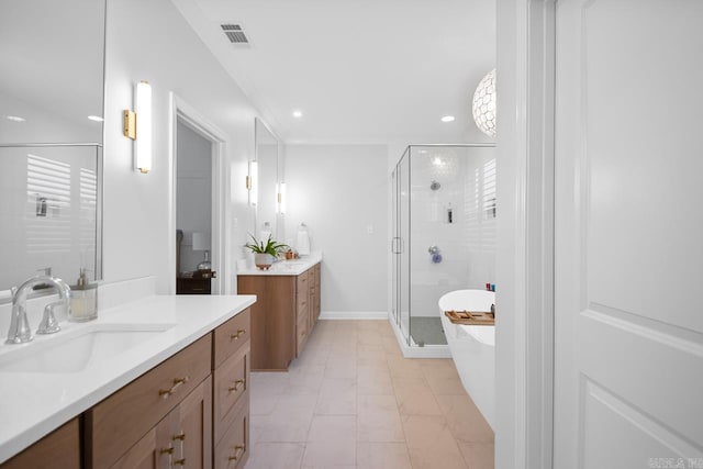 full bath with visible vents, a sink, a freestanding tub, a shower stall, and two vanities