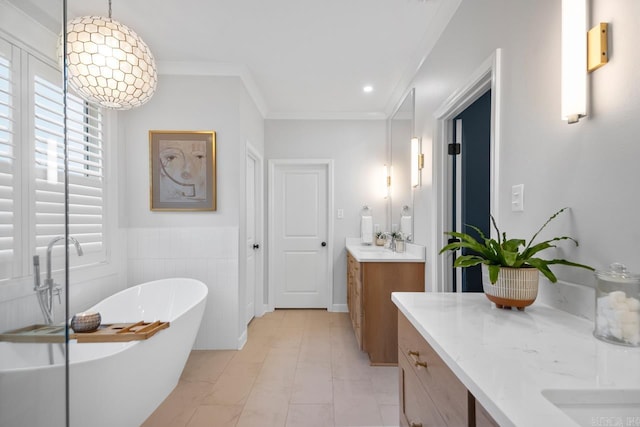 bathroom with crown molding, recessed lighting, two vanities, a freestanding bath, and a sink