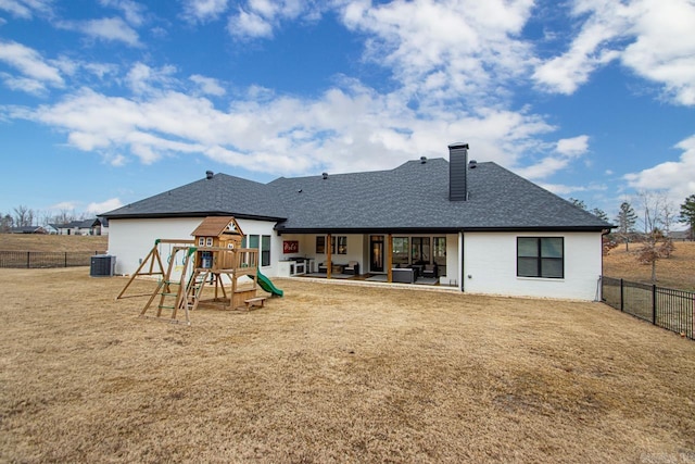 rear view of house with a playground, a patio, a lawn, central AC, and a fenced backyard