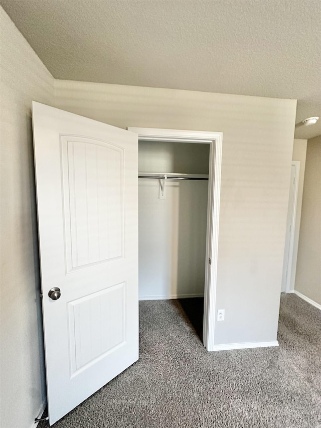 unfurnished bedroom featuring a textured ceiling, a closet, carpet, and baseboards